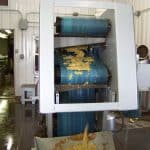 Dry pumace falls from the press belts onto an elevator and outside